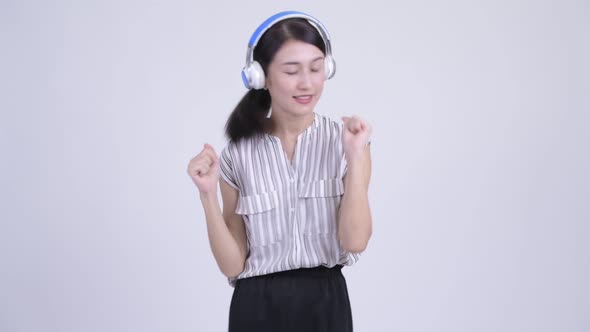 Beautiful Asian Businesswoman Listening To Music and Looking Guilty