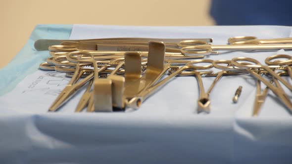 Close-up of a sterile surgical tray full of operating instruments with motion a healthcare worker mo