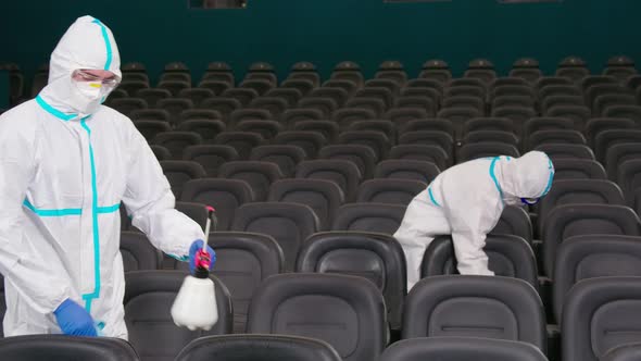Two Workers Wiping Chairs with Disinfectants in Cinema