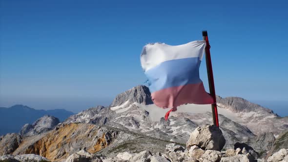 Slow motion footage of a tattered Russian flag developing in the wind. In the background is a blue s
