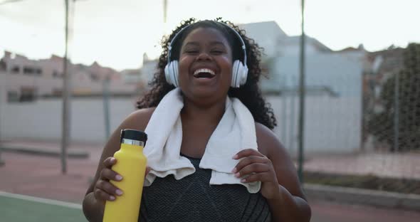 Curvy african woman smiling in camera while doing workout routine outdoor 