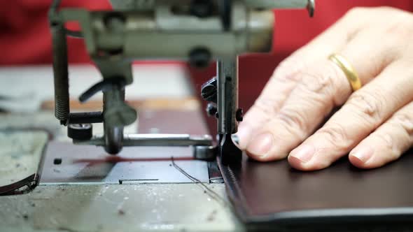 Close-Up Of Tailor Working On Sewing Machine in leather factory background