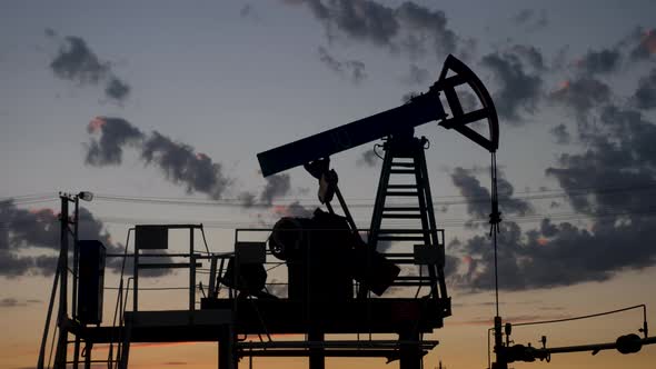 Oil Rig Stands in a Field at Sunset and Extracts Minerals