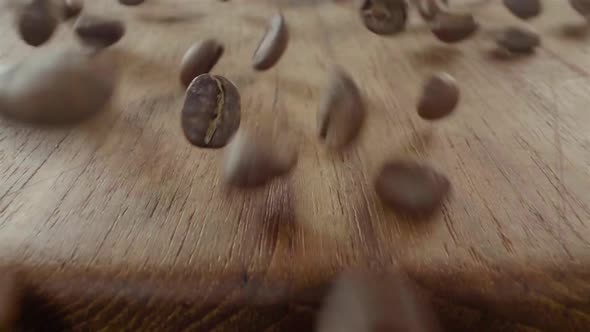 Many coffee beans dropped on a wooden table and falling into a big container. Epic macro food shot,