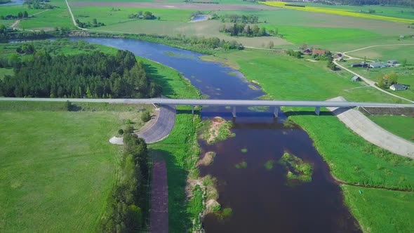 Aerial view of a Venta river (Latvia) on a sunny summer day, lush green trees and meadows, beautiful