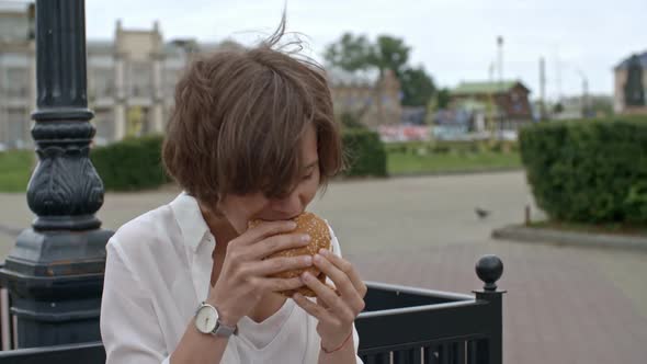 Businesswoman Eating Burger and Using Tablet Outdoors