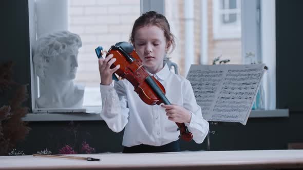 A Little Girl Putting Together the Violin Piece By Piece Before Playing