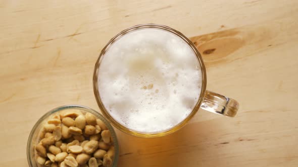 Top View of Beer with Foam and Salty Peanuts and on Wooden Table