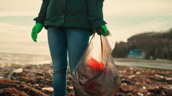 A Young Female Volunteer Wearing Rubber Gloves Holding a Garbage Bag