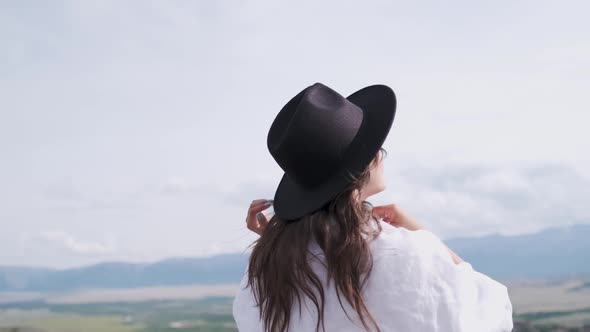 Attractive Brunette in a Hat and White Shirt Is Enjoying Nature in the Mountains. Beautiful Young