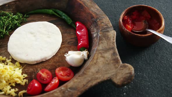 Pizza dough with vegetables and spices on wooden tray