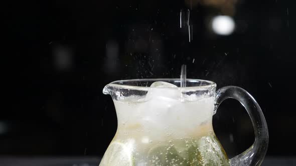 Sparkling Soda Water Being Poured Into Glass Jar Filled with Sliced Lime Mint Leaves and Ice