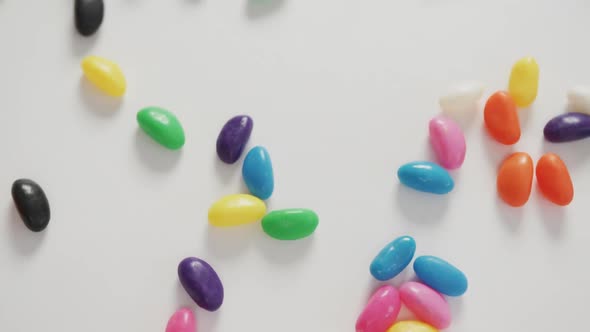 Video of close up of multi coloured sweets spinning over white background