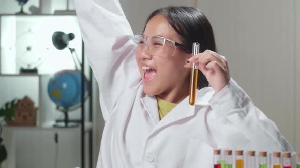 Excited Young Asian Scientist Girl Mixes Chemicals In Test Tube. Child Learn With Interest