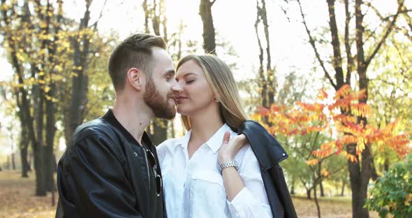 Happy Couple in Love Kissing Each Other in Embraces in Autumn Park