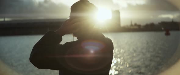 A man listening music next to the river with backlight contrast