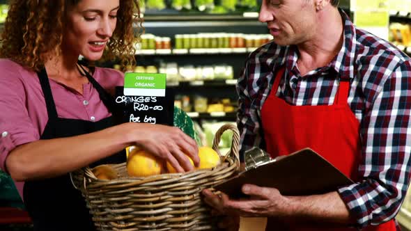Staff maintaining record of fruits on clipboard in organic section