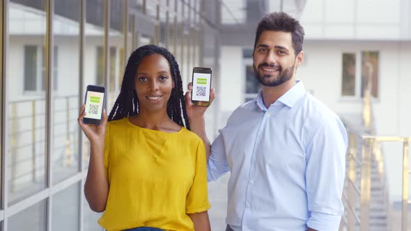 Multiethnic Couple Looking at Camera Showing Vaccinated Qrcode on Cellphone