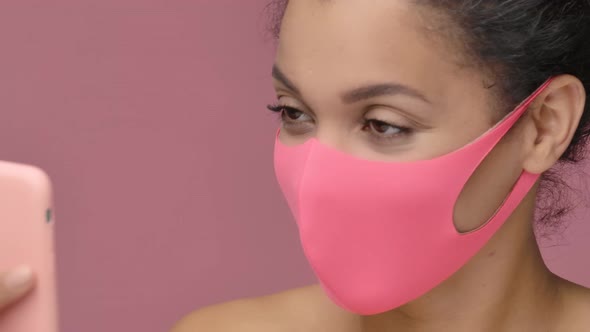 Beauty Portrait of Young African American Woman in Pink Protective Mask Taking Selfie Using