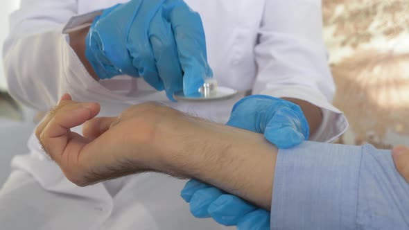 Close up doctor measures pressure female patient tonometer while sitting on sofa in bright office