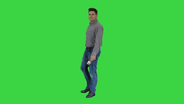 Casual Man with Brush and Some Liquid Looking What To Paint and Smiling To Camera on a Green Screen