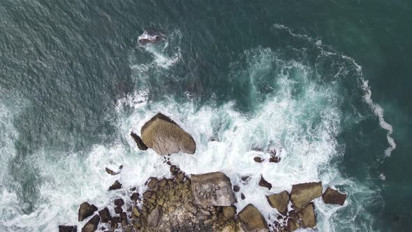 Top down aerial view of giant ocean waves crashing and foaming in coral beach