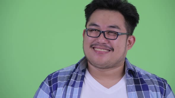 Face of Happy Young Overweight Asian Hipster Man Thinking