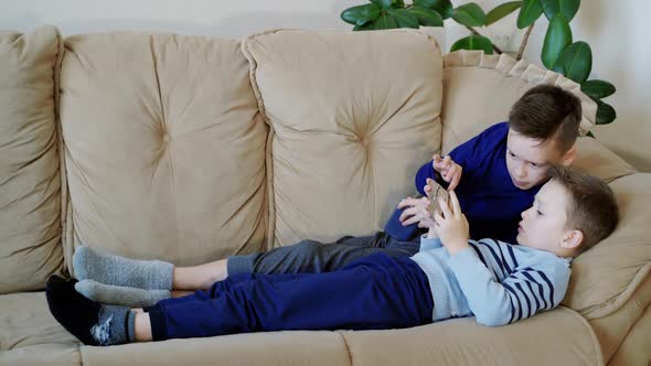 Preschool boys holds modern mobile phone and plays cheerfully video game. Focus on smartphone.