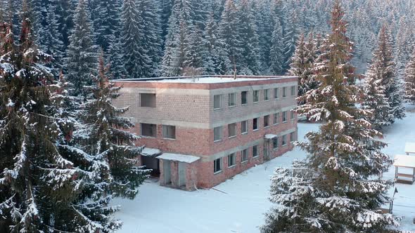 Degraded Building Surrounded By Snowy Pine Trees In Winter Forest - Wide Shot