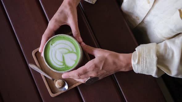 Top View of Woman Holding in Hands Trendy Green Matcha Drink with Amazing Latte Art in the Hipster