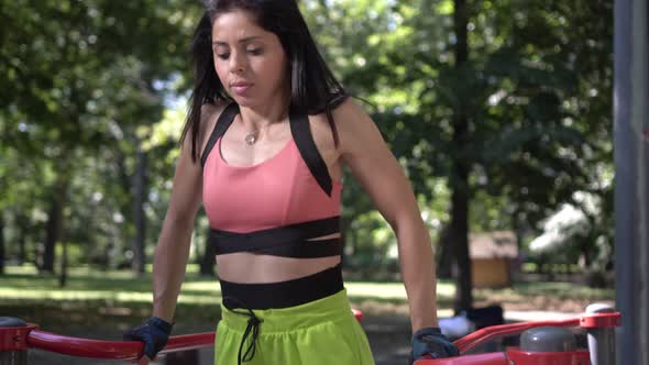 Athletic Woman Doing Pushups on the Uneven Bars Outdoors