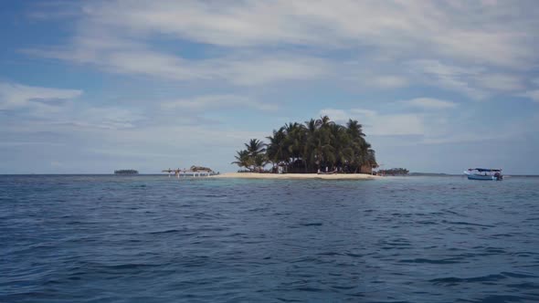 Little island with palms and building between water