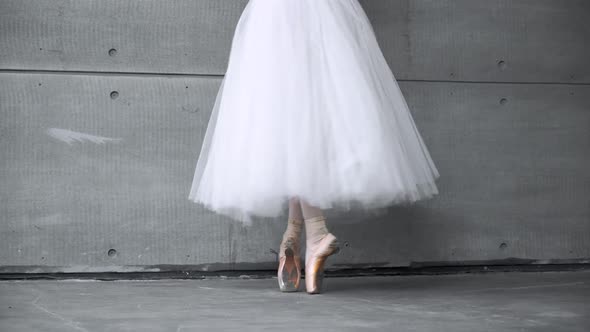 Elegant Female in a White Tutu Dance Ballet and Balancing in Pointe Shoes View of the Legs Gray