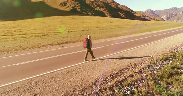 Flight Over Hitchhiker Tourist Walking on Asphalt Road