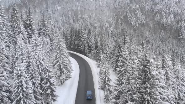 Aerial View of a Car Driving Along the Mountain Road in Winter