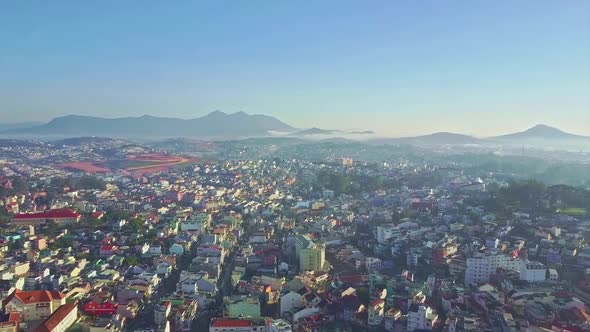 Flycam Hangs Above City Located Among Green Hills