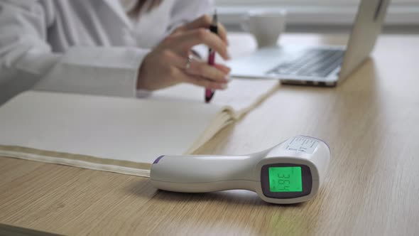 Close Up View of Noncontact Infrared Thermometer Medical Equipment with Female Doctor Working in