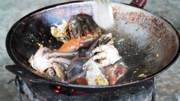 Cooking fresh crab meat in wok style pan over charcoal fire
