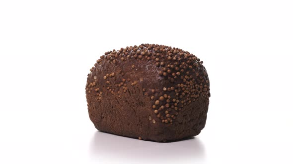 Beautiful Loaf of Black Bread with Sprinkles Spinn on White Background