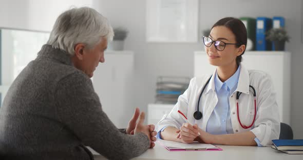 Aged Man Patient Talking to Doctor in Clinic Office