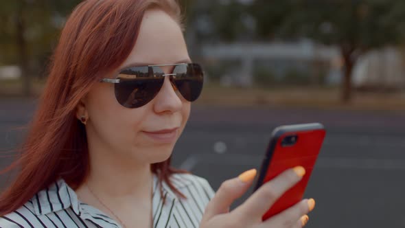 Young Woman in Sunglasses with Mobile Phone on Street in Summertime