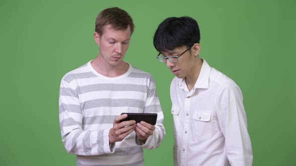 Two Young Multi-ethnic Businessmen Using Phone Together