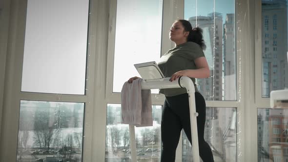 Woman is running on treadmill at home, doing aerobic fitness workout in the morning