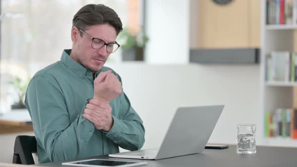 Middle Aged Man Having Wrist Pain While Working on Laptop