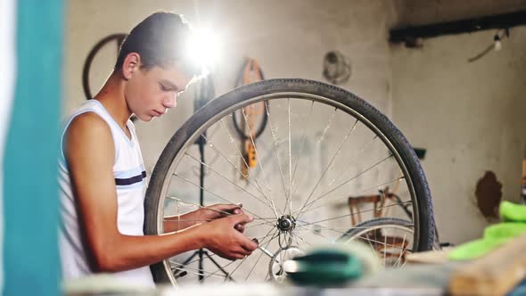 Teenager Working on the Wheel of His Bicycle