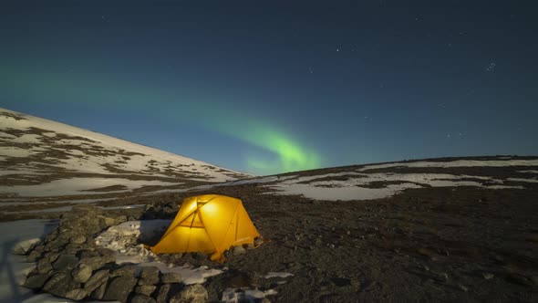 Green Northern Lights Over Glowing Tent in Khibiny Mountains