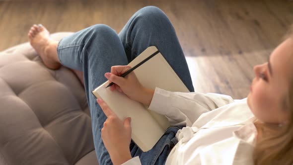 Model Poses Writing Notes in a Notebook