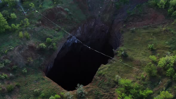 Aerial Footage of a Massive Natural Pit with a Rope Stretched Over It Slackline