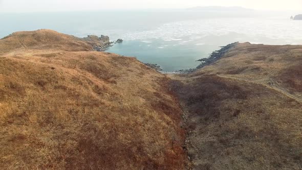 Drone View of a Rocky Bay Surrounded By a Hill Covered with Yellowed Grass