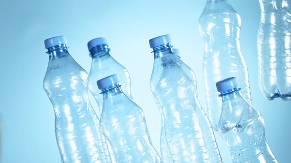 Super Slow Motion Shot of Flying Empty Plastic Bottles on Light Blue Gradient Background at 1000Fps